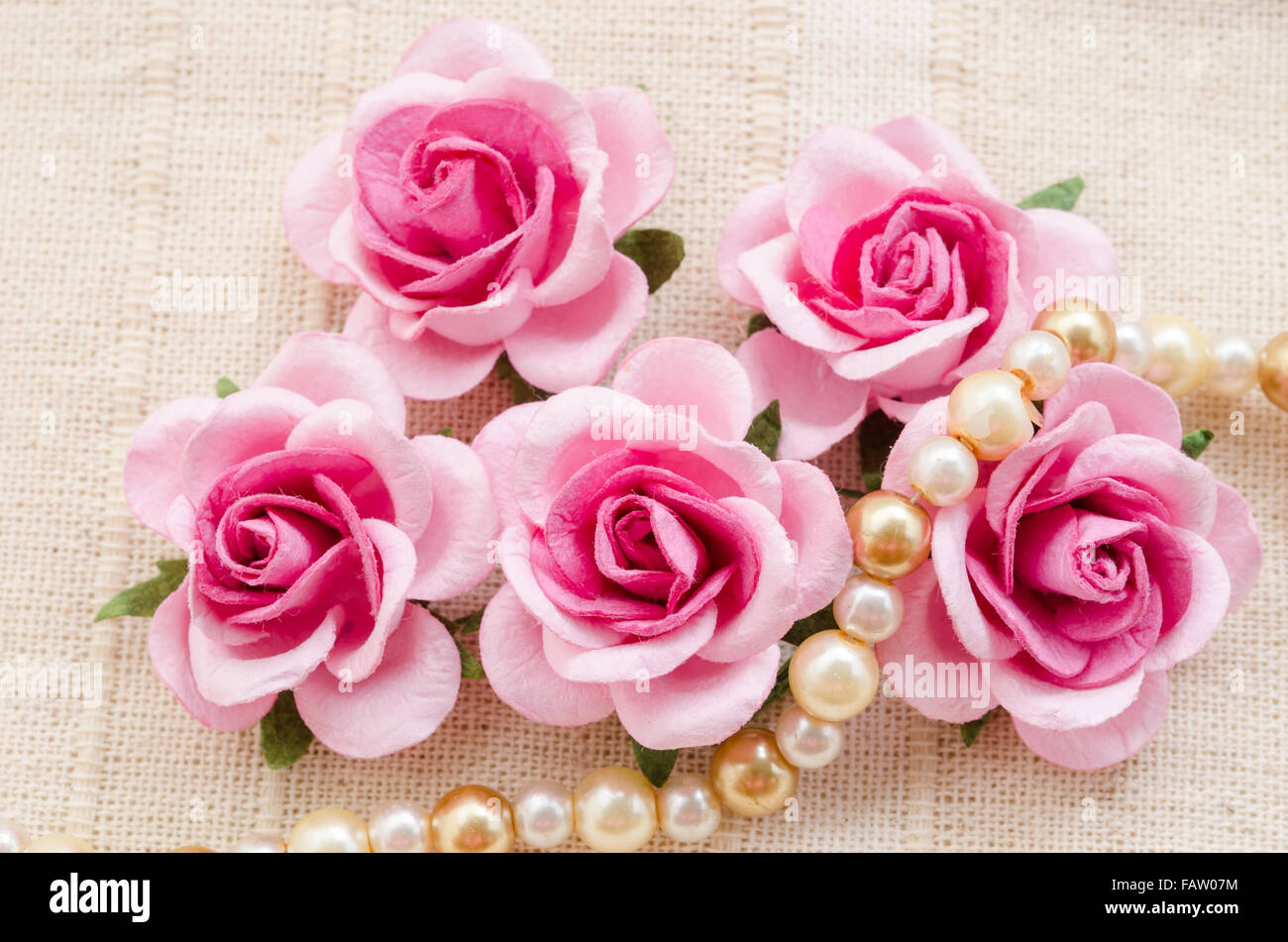 Pink rose with pearls on fabric background. Stock Photo