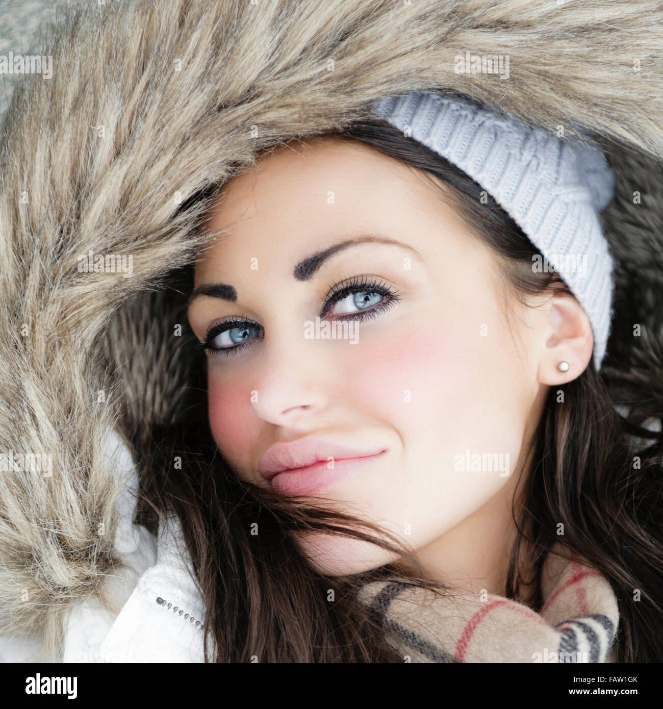 Outdoor beauty portrait of beautiful attractive young woman in warm fur lined hooded winter coat or jacket  Model Release: Yes.  Property release: No. Stock Photo