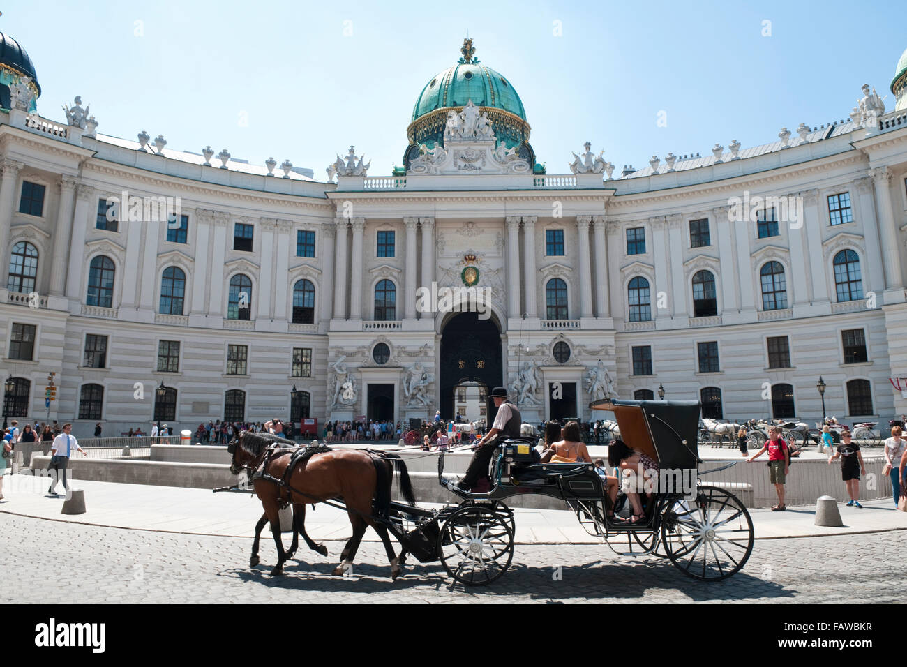 A traditional fiaker horse-drawn carriage going past the Michaelertrakt ...