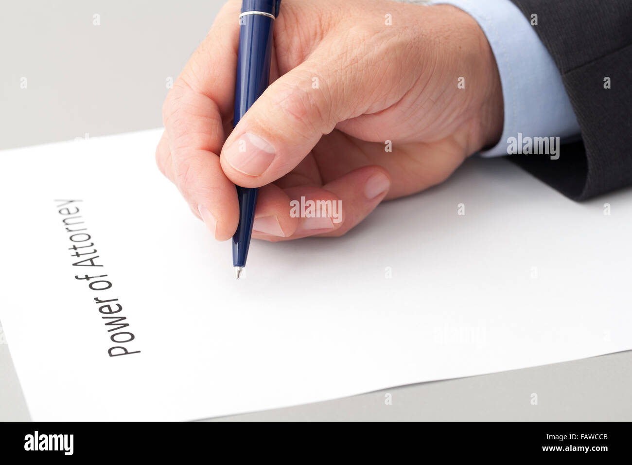 Businessman with a pen in the hand, writing a power of attorney document. The sheet is on the table Stock Photo