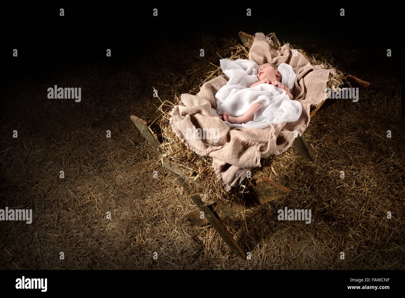 New born Jesus laying on a manger over dark background Stock Photo