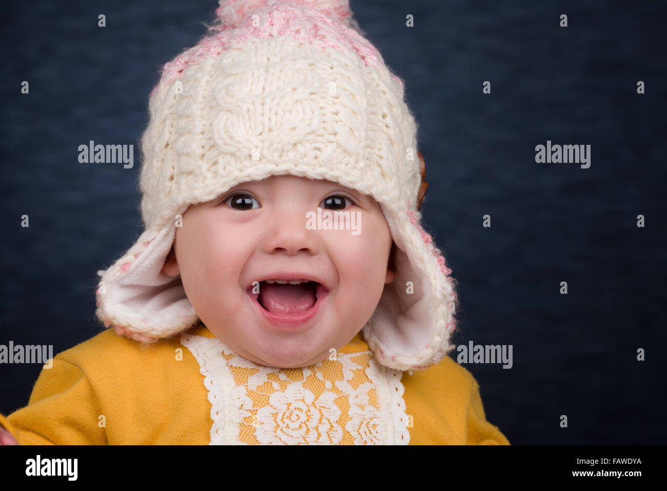 A smiling baby girl wearing a knit winter hat. Stock Photo
