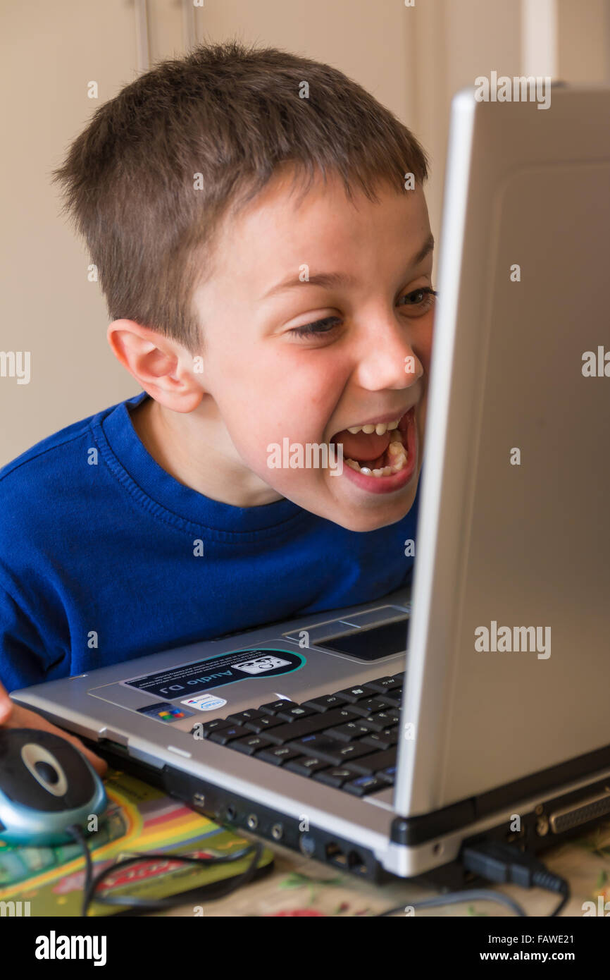 Joking Child in Front of Touch Screen Laptop, tongue stuck out Stock Photo