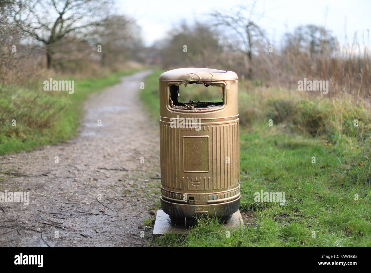A gold painted litter bin - fire damaged, on a countryside walk in the UK Stock Photo