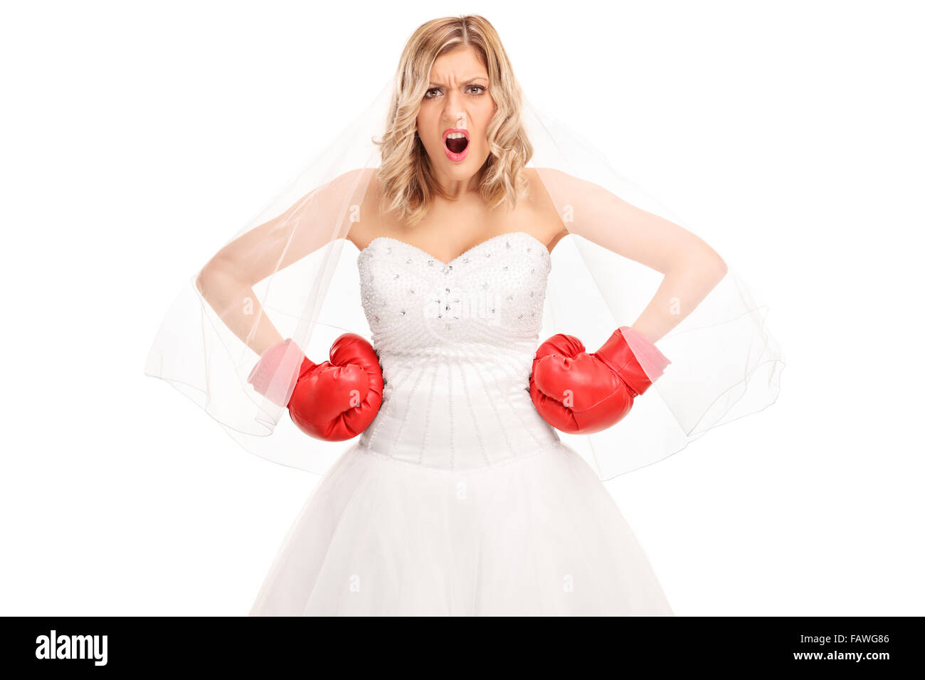 Angry bride in a white wedding dress and red boxing gloves looking at the camera isolated on white background Stock Photo