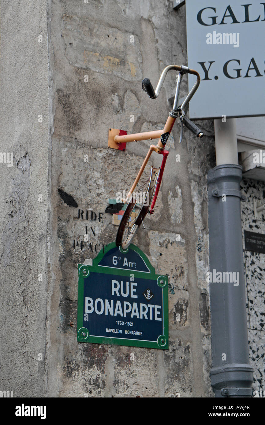 Part of a bicycle (and a 'Ride in Peace' painted tag) above the road sign for Rue Bonaparte, Paris, France. Stock Photo