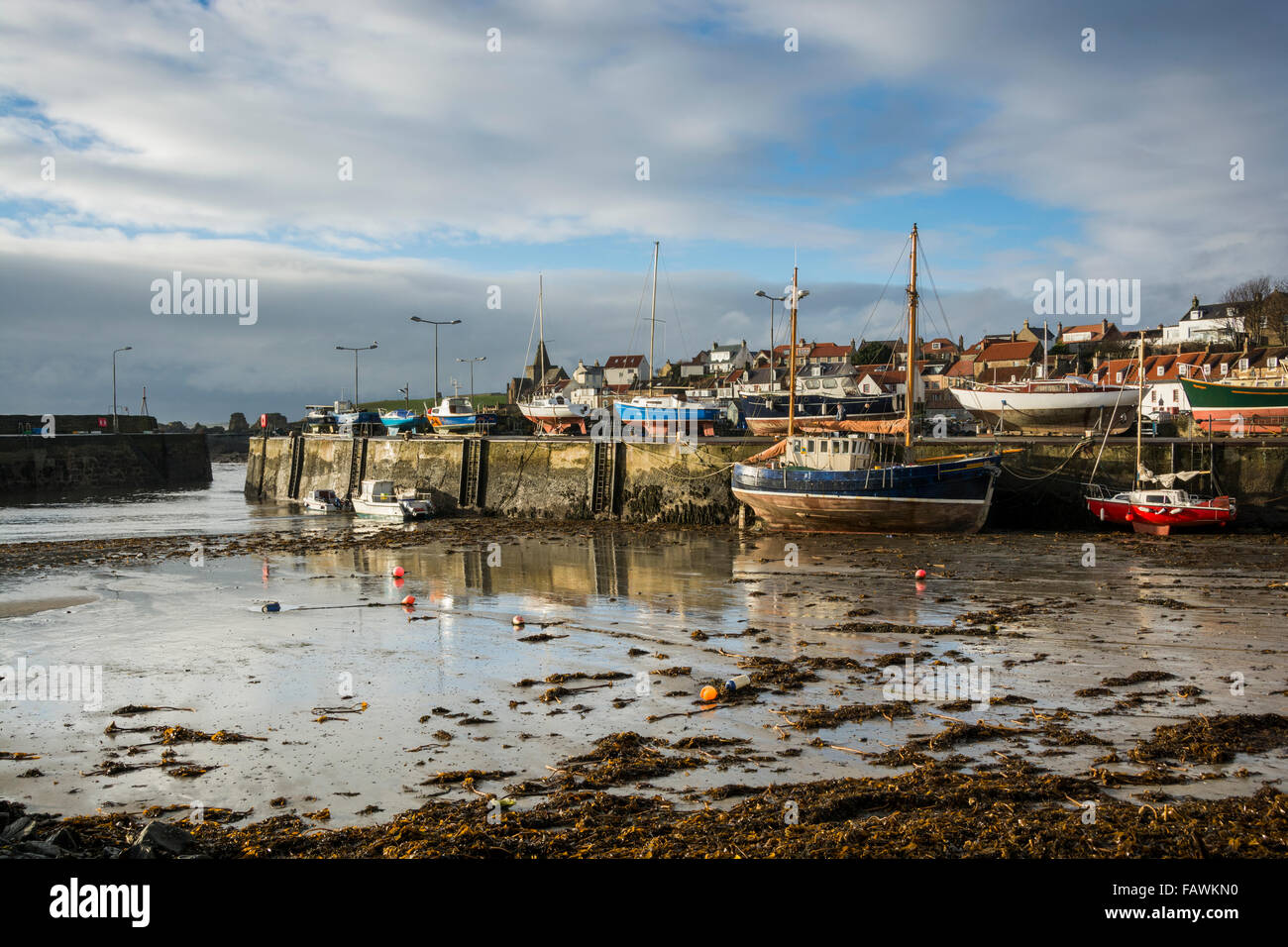 Boats moored against the harbour wall of the fishing village of St Monan's on the coast of Fife in Scotland. Stock Photo