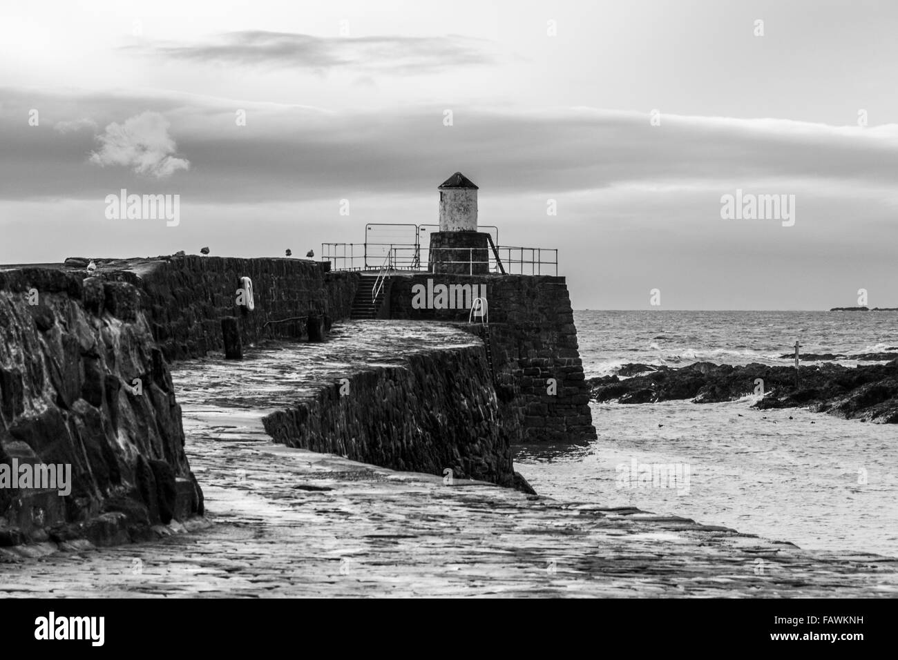 Harbour wall with lighthouse at the end in the pretty fishing village of Pittenweem on the coast of Fife, Scotland Stock Photo