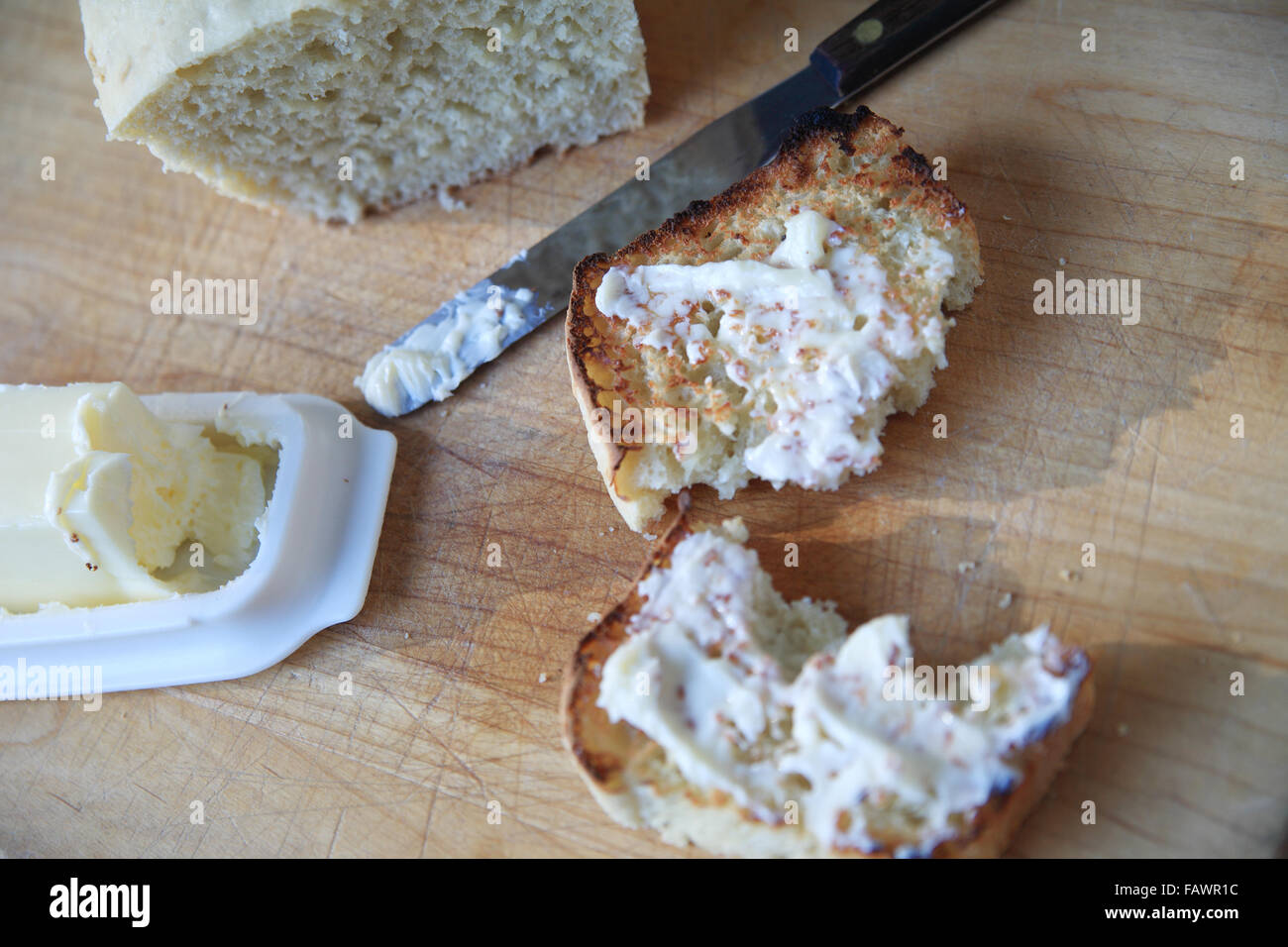 Buttered toast with spreader, loaf of homemade bread and butter dish on