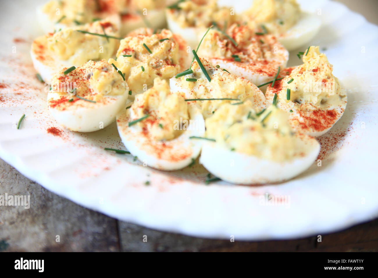 Deviled eggs with smoked paprika and chives on a white fluted platter