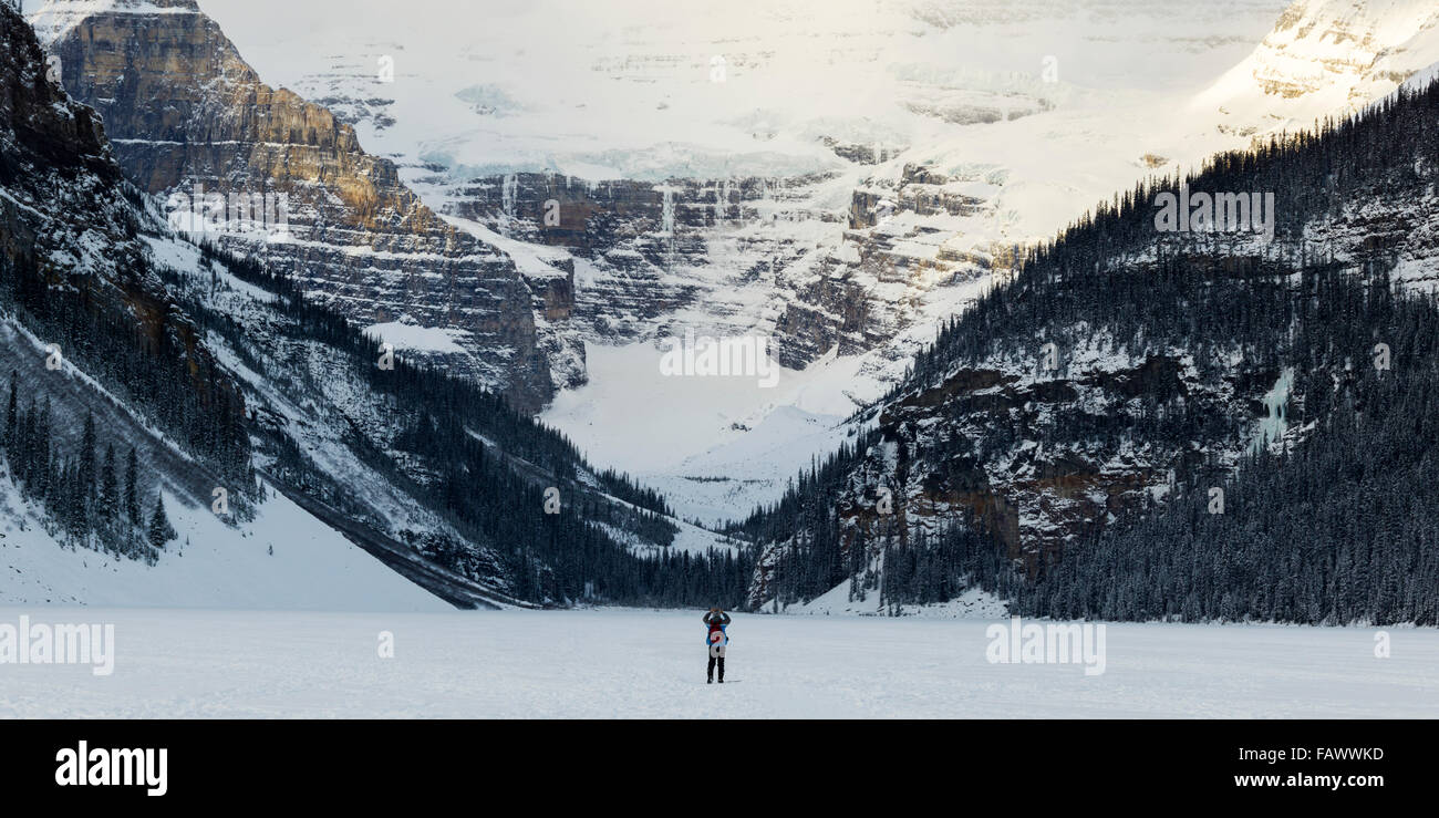 A person standing on frozen Lake Louise taking a picture of the snow ...
