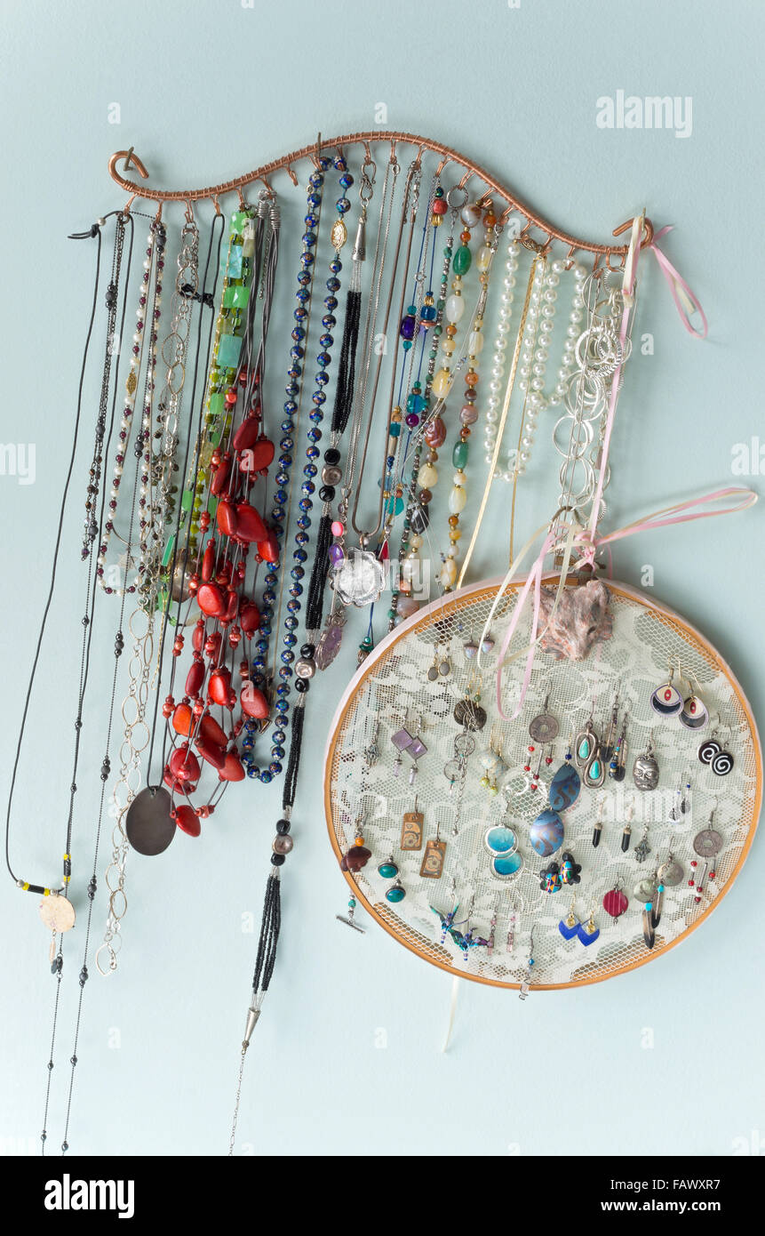 jewelry organizer hanging on wall with earrings necklaces pendants and other finery Stock Photo