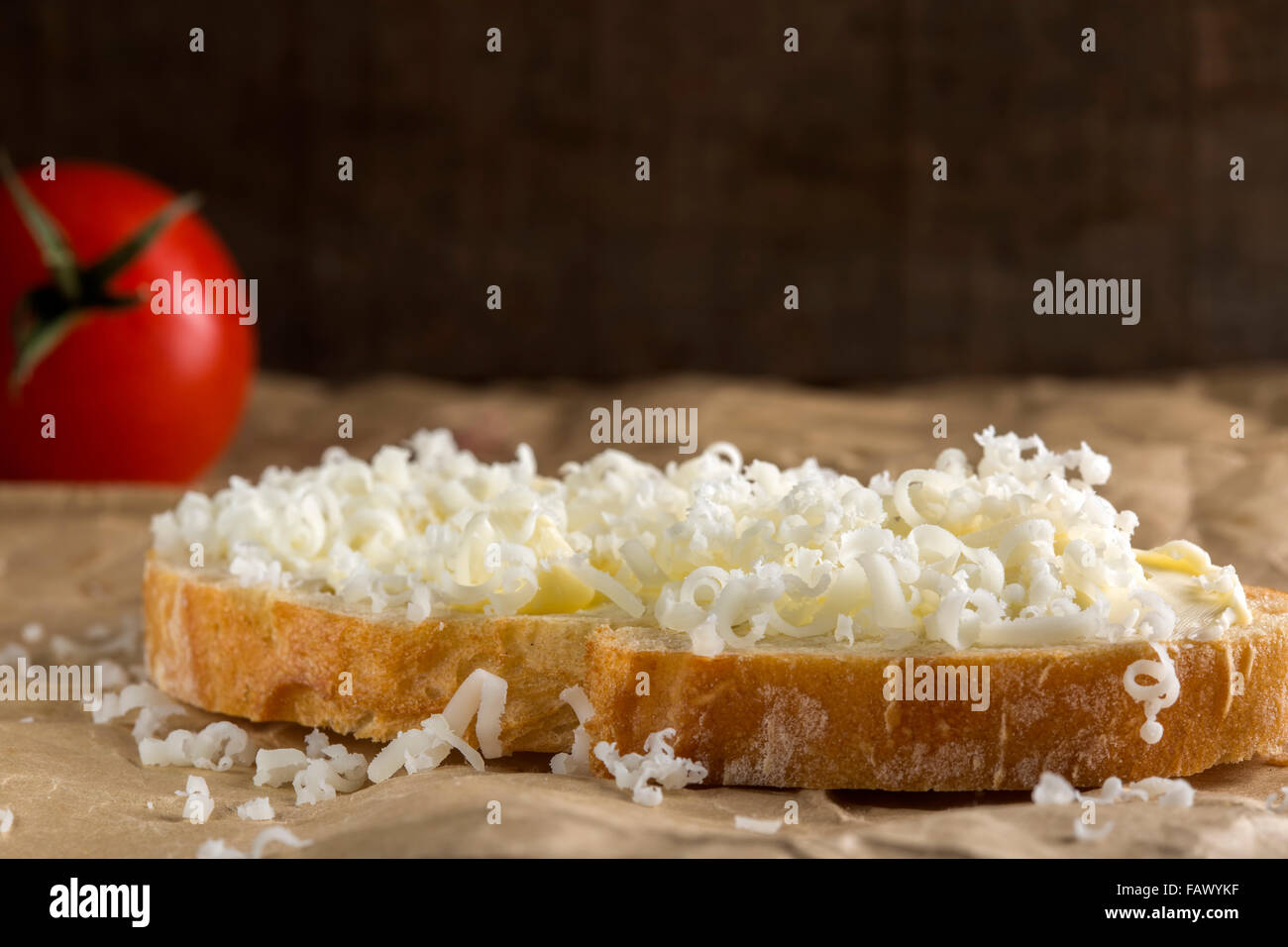 Slice of bread with butter and grated cheese over paper Stock Photo