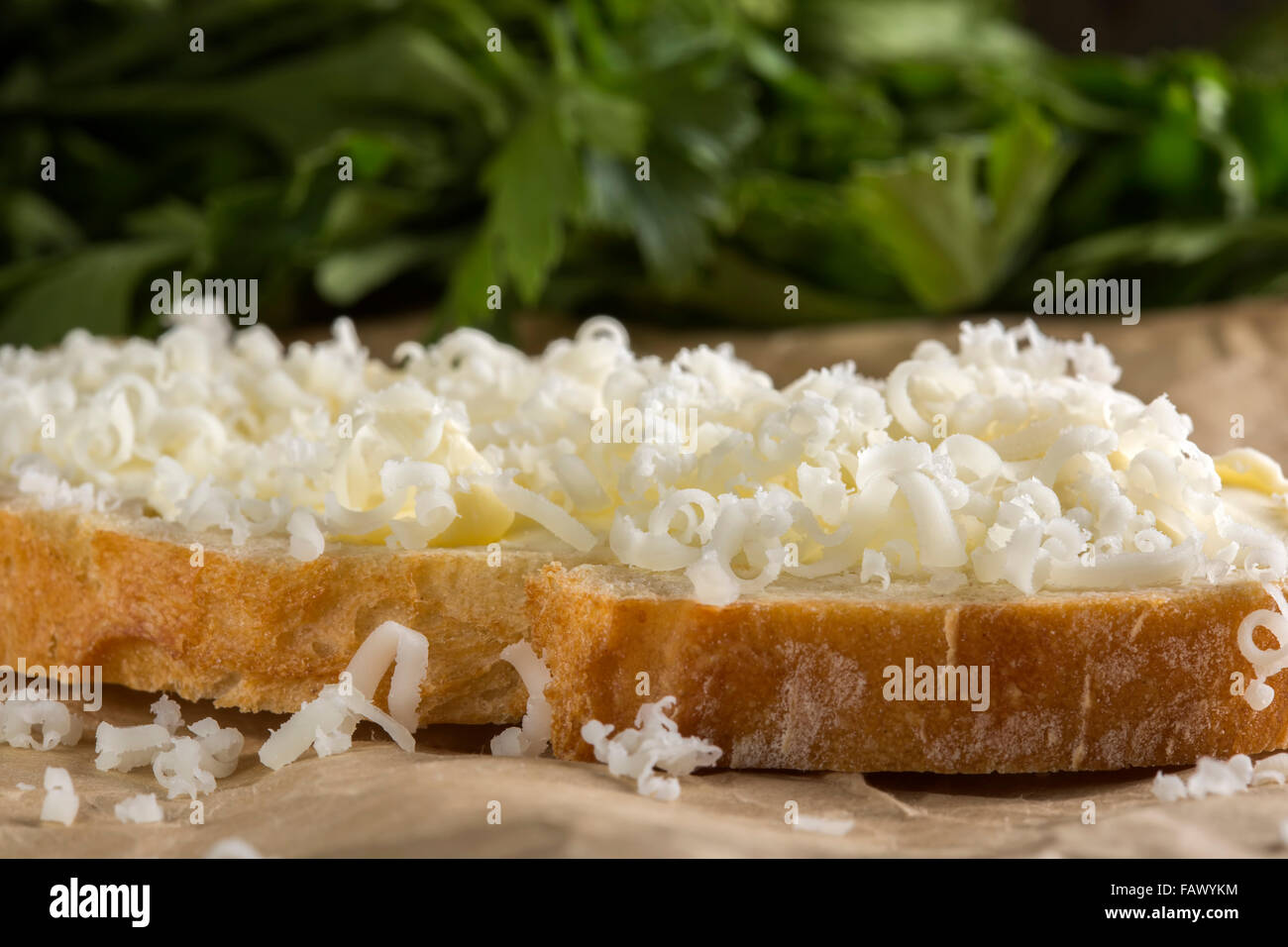 Slice of bread with butter and grated cheese over paper Stock Photo