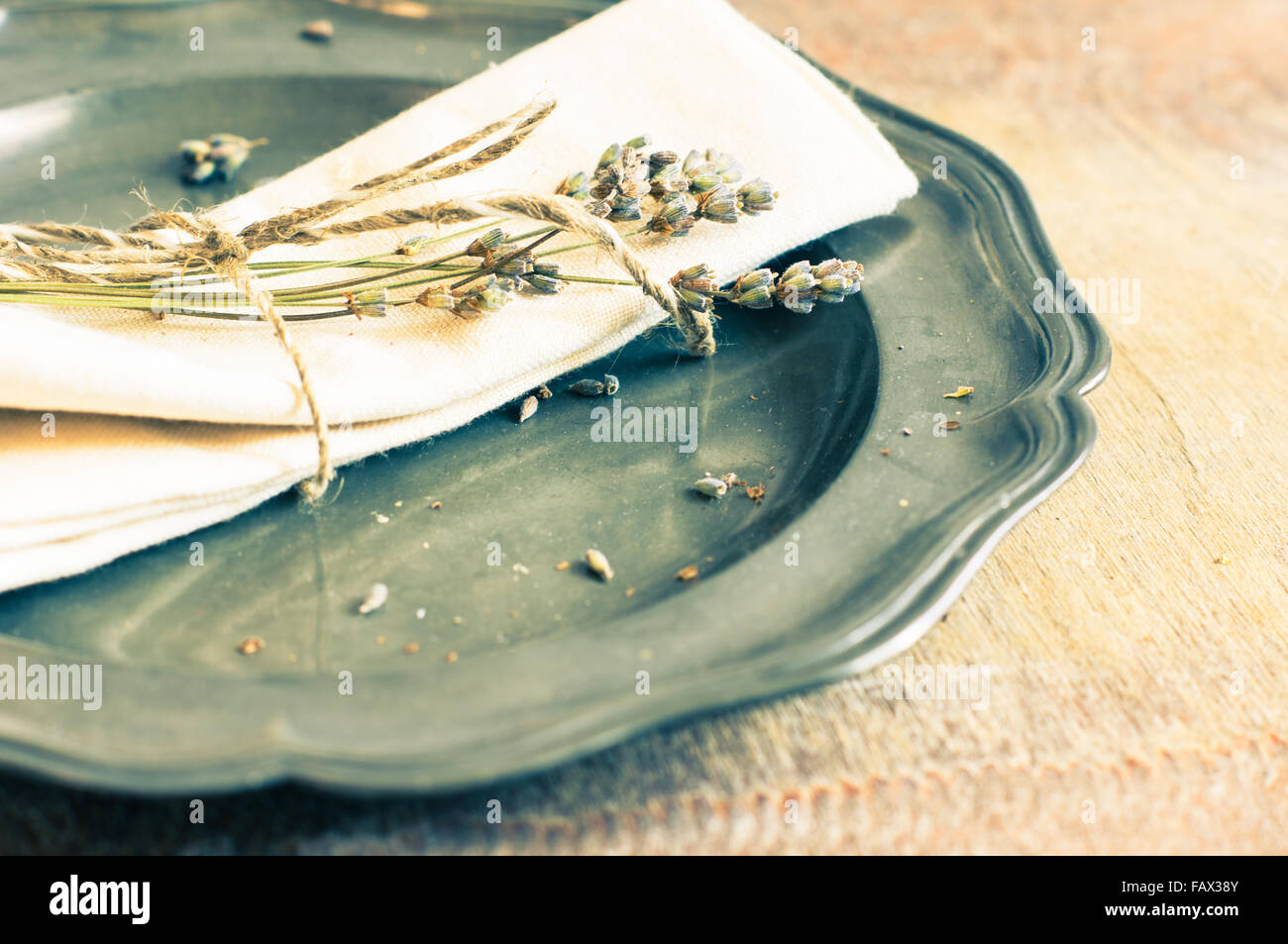 Rustic table setting with vintage silverware and plate with dried lavender flowers. Toned image Stock Photo