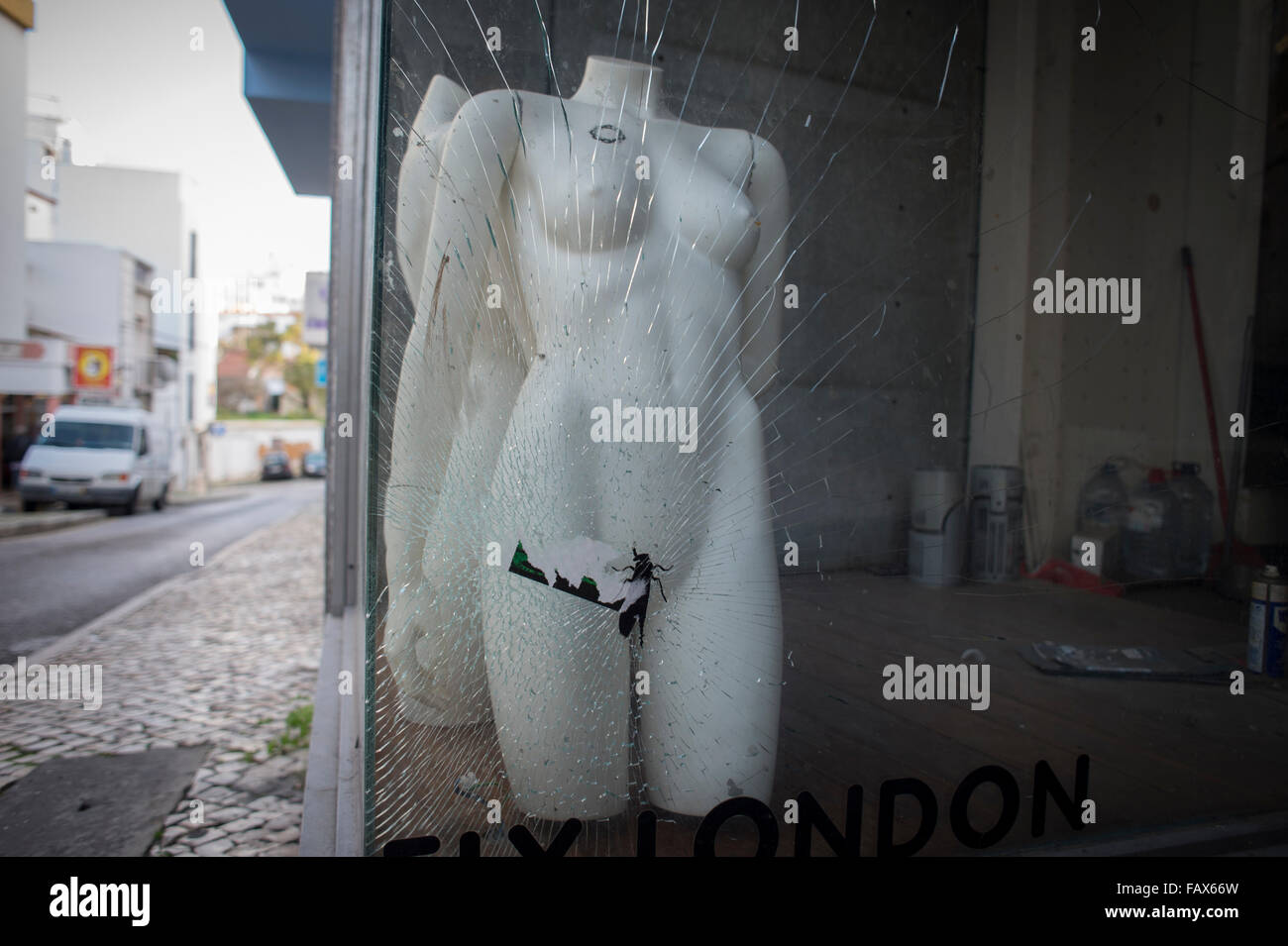 naked clothes mannequin in a shop window with broken glass Stock Photo