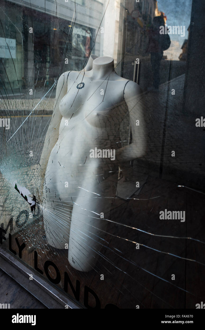 naked clothes mannequin in a shop window with broken glass Stock Photo