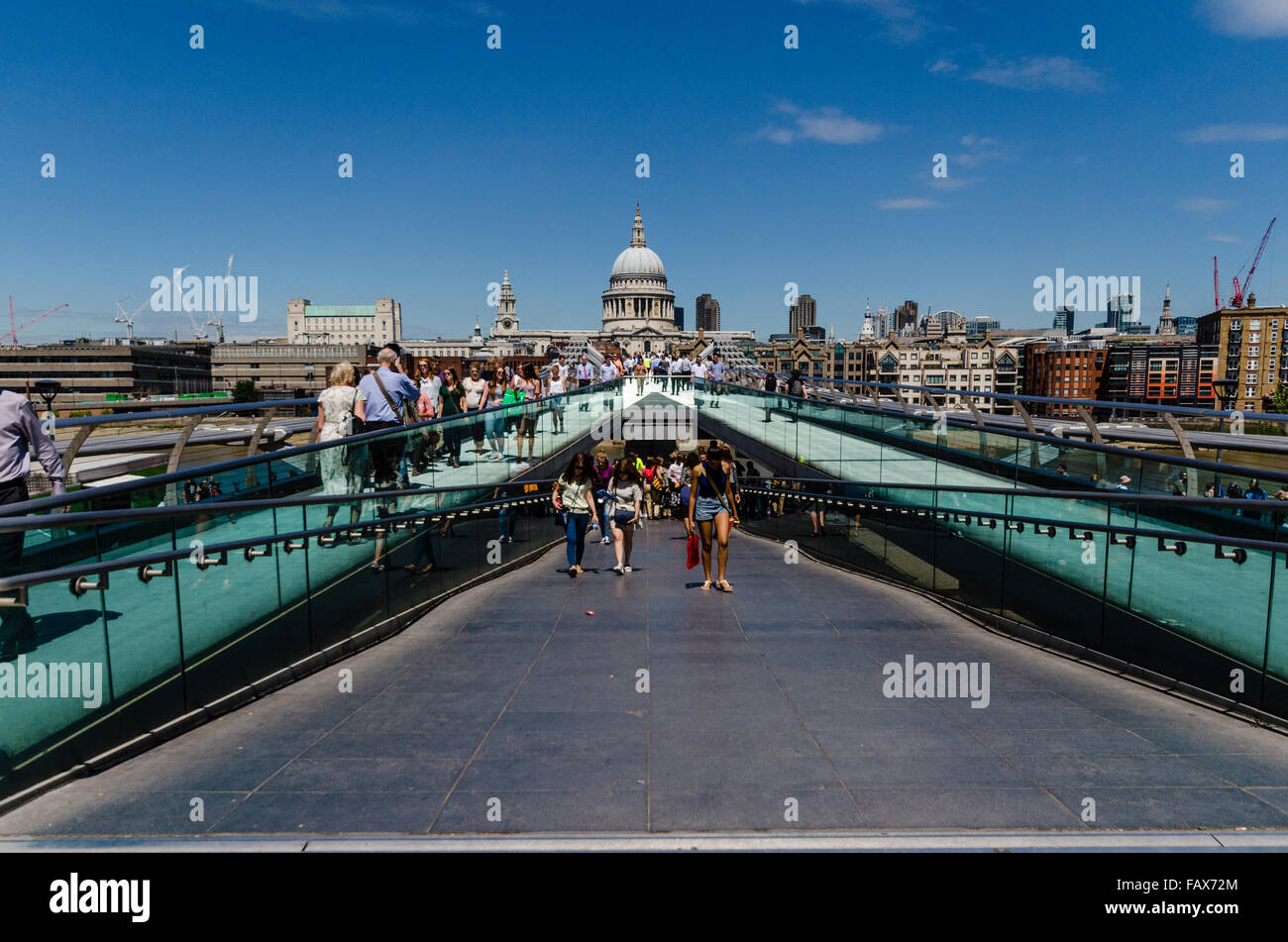 People walking over London Millennium Footbridge. Saint Pauls Cathedral in view. Stock Photo