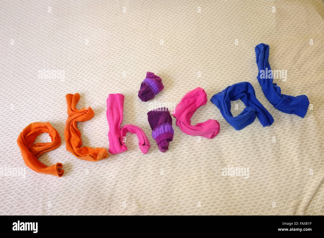 The word ethical made out of colourful socks laying on a duvet cover. Stock Photo