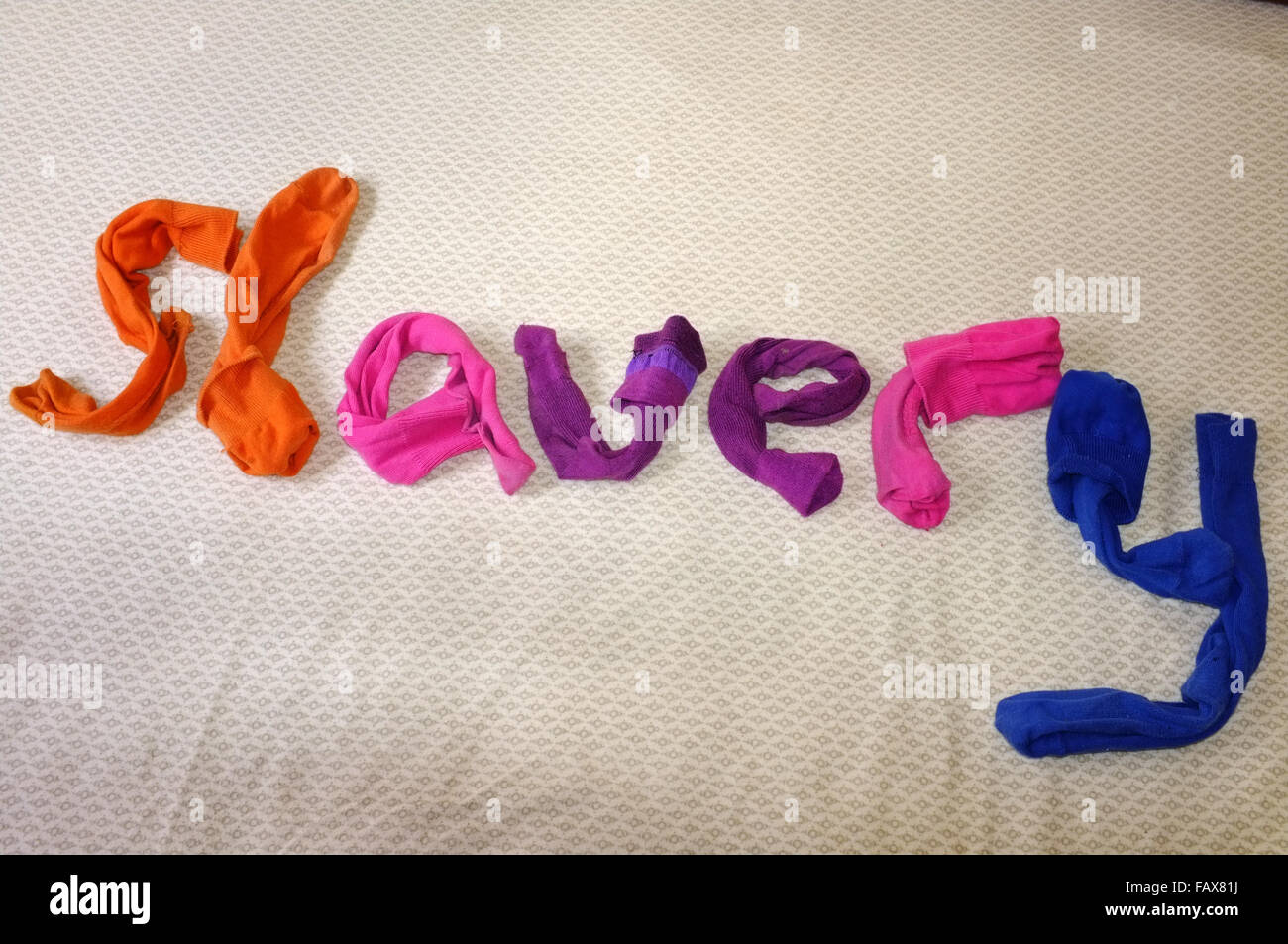 The word slavery made out of colourful socks laying on a duvet cover. Stock Photo