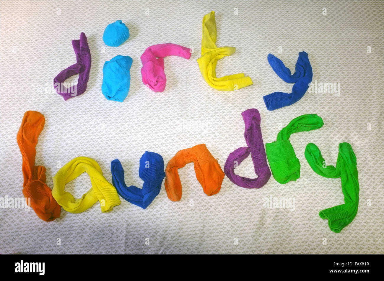 The word laundry made out of colourful socks laying on a duvet cover. Stock Photo