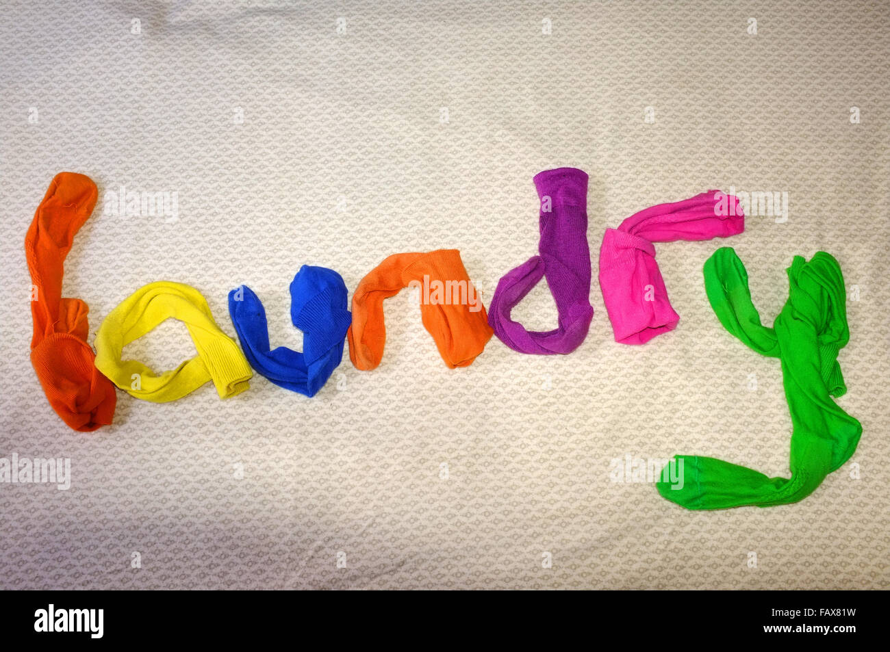 The word laundry made out of colourful socks laying on a duvet cover. Stock Photo
