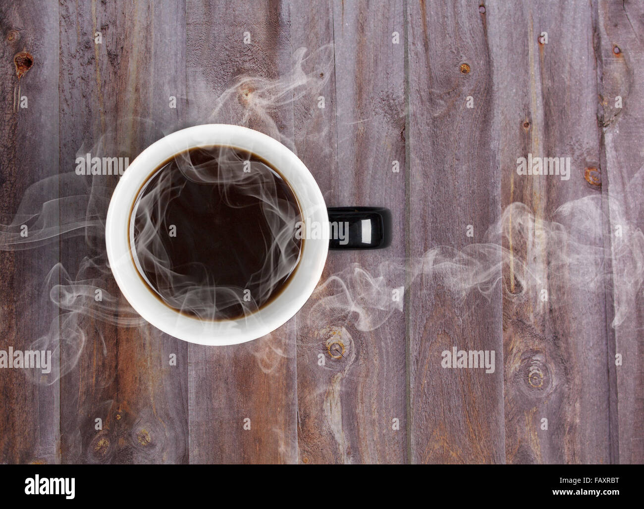 Coffee mug placed on wooden table with steaming hot black coffee Stock Photo