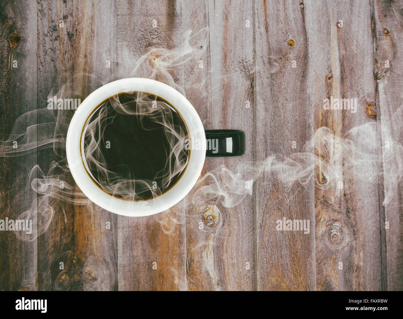 Coffee mug placed on wooden table with steaming hot black coffee - retro instagram film look filter Stock Photo