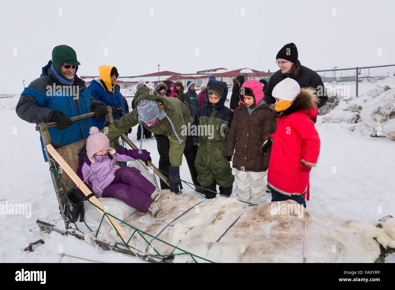 Elementary school kids wearing winter gear wait to ride a sled around the lagoon, Barrow, North Slope, Arctic AK, USA, Winter Stock Photo