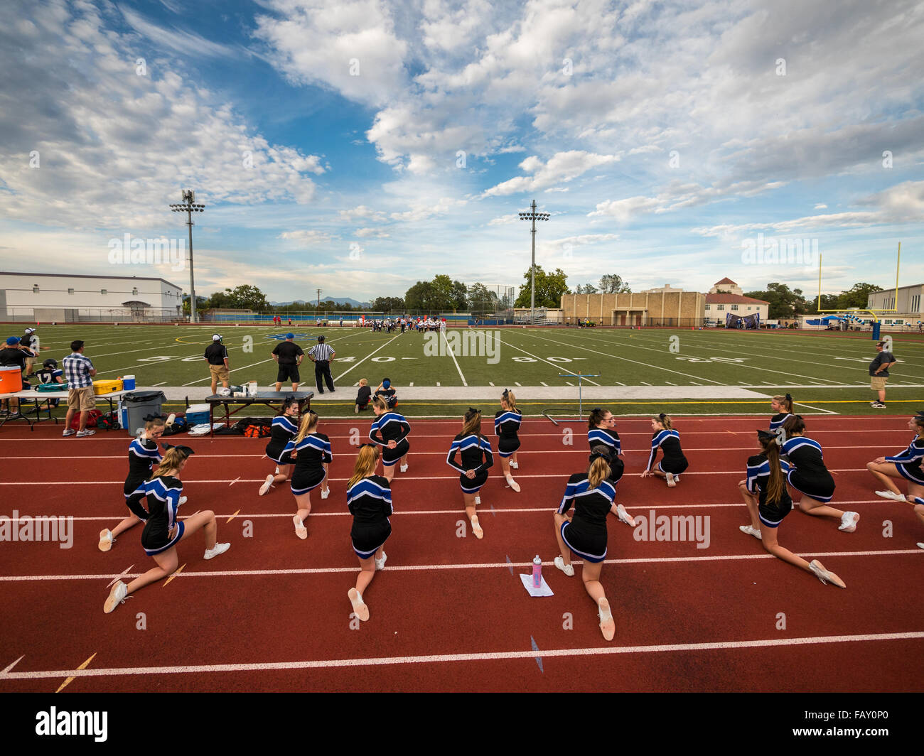 REDDING, CALIFORNIA, USA - OCTOBER 23, 2015: Teenage cheerleaders kneel during a time out at high school football game. Stock Photo
