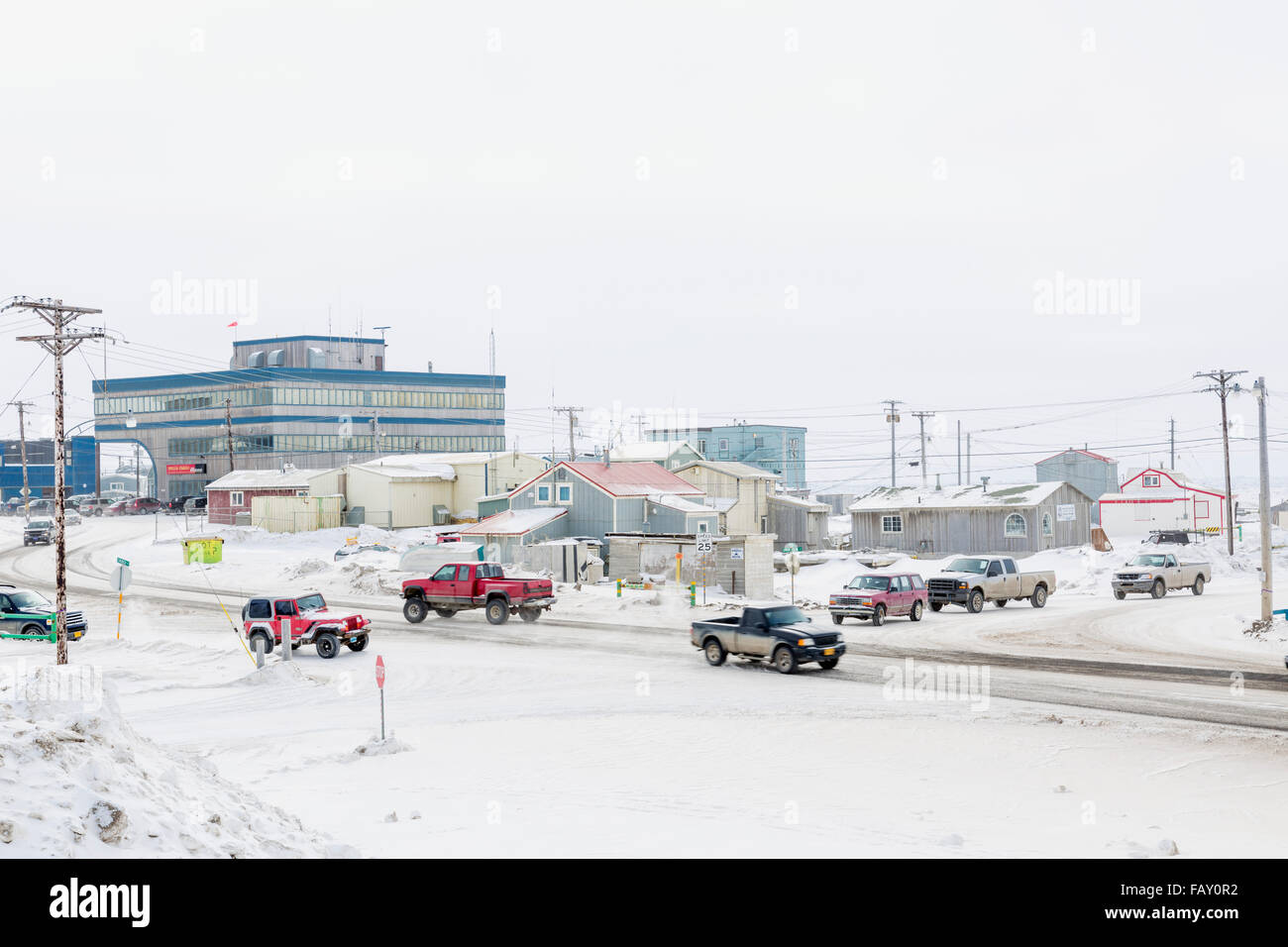Cars and trucks drive on snow covered road in downtown Barrow, North