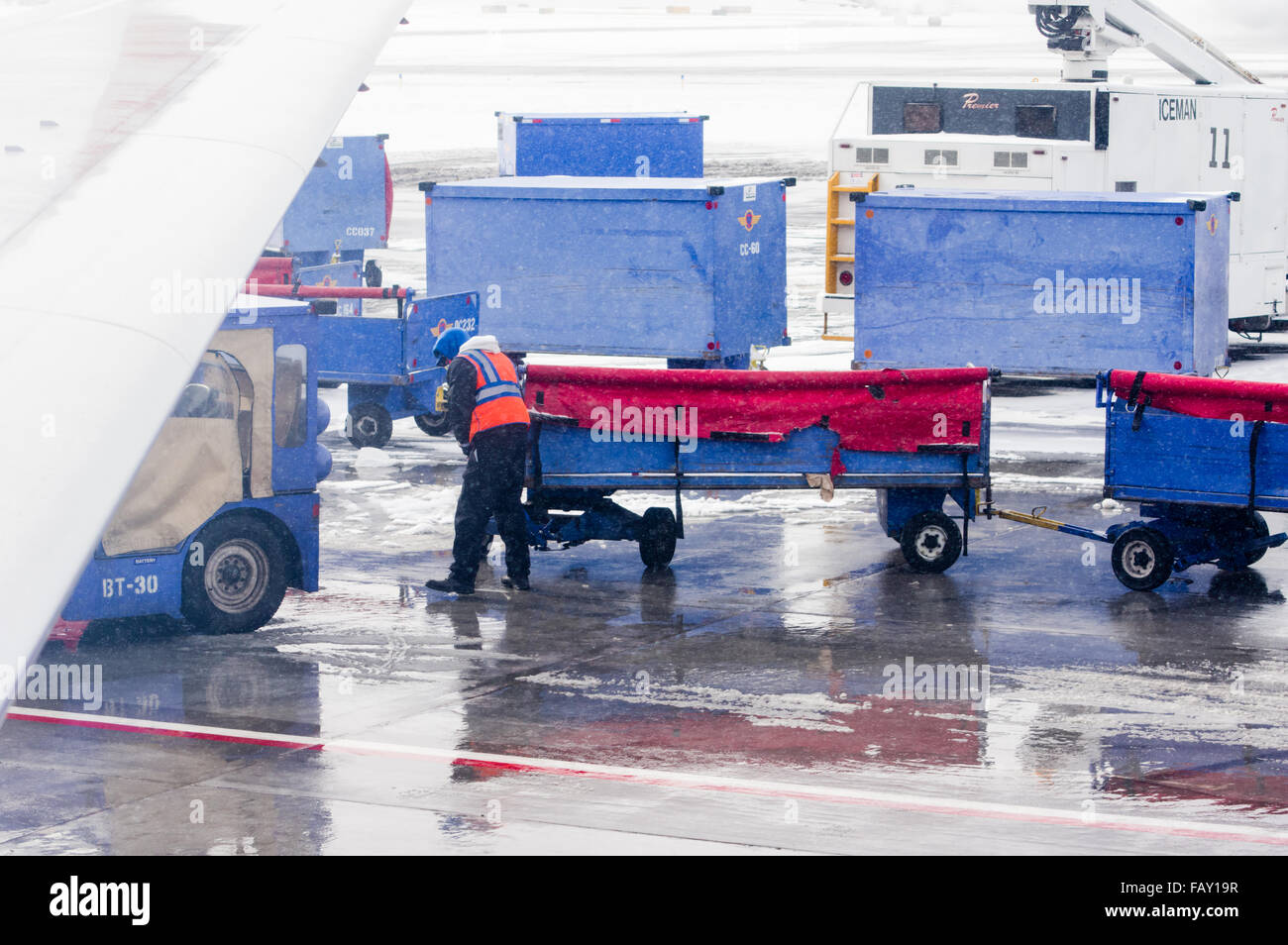 Baggage handler working with carts during a snow storm at Denver International Airport, Denver Colorado Stock Photo