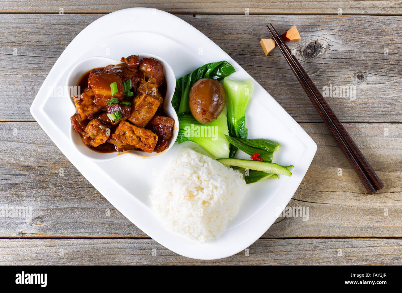 Top view of succulent Chinese dish with fried tofu, bok choy, soy sauce egg, cucumber, rice and chopsticks in holder Stock Photo