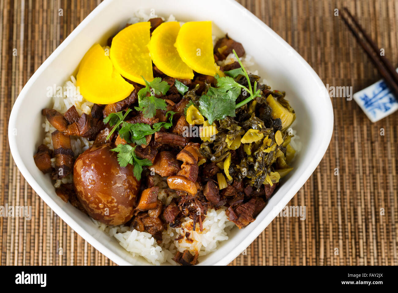 Top view of Asian dish with sliced pork, soy sauce egg, pickles, rice and chopsticks. Stock Photo