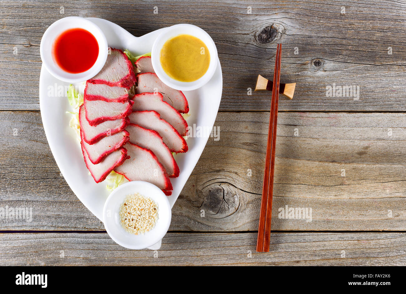 Top view Chinese sliced pork with special sauces on rustic wood. Stock Photo