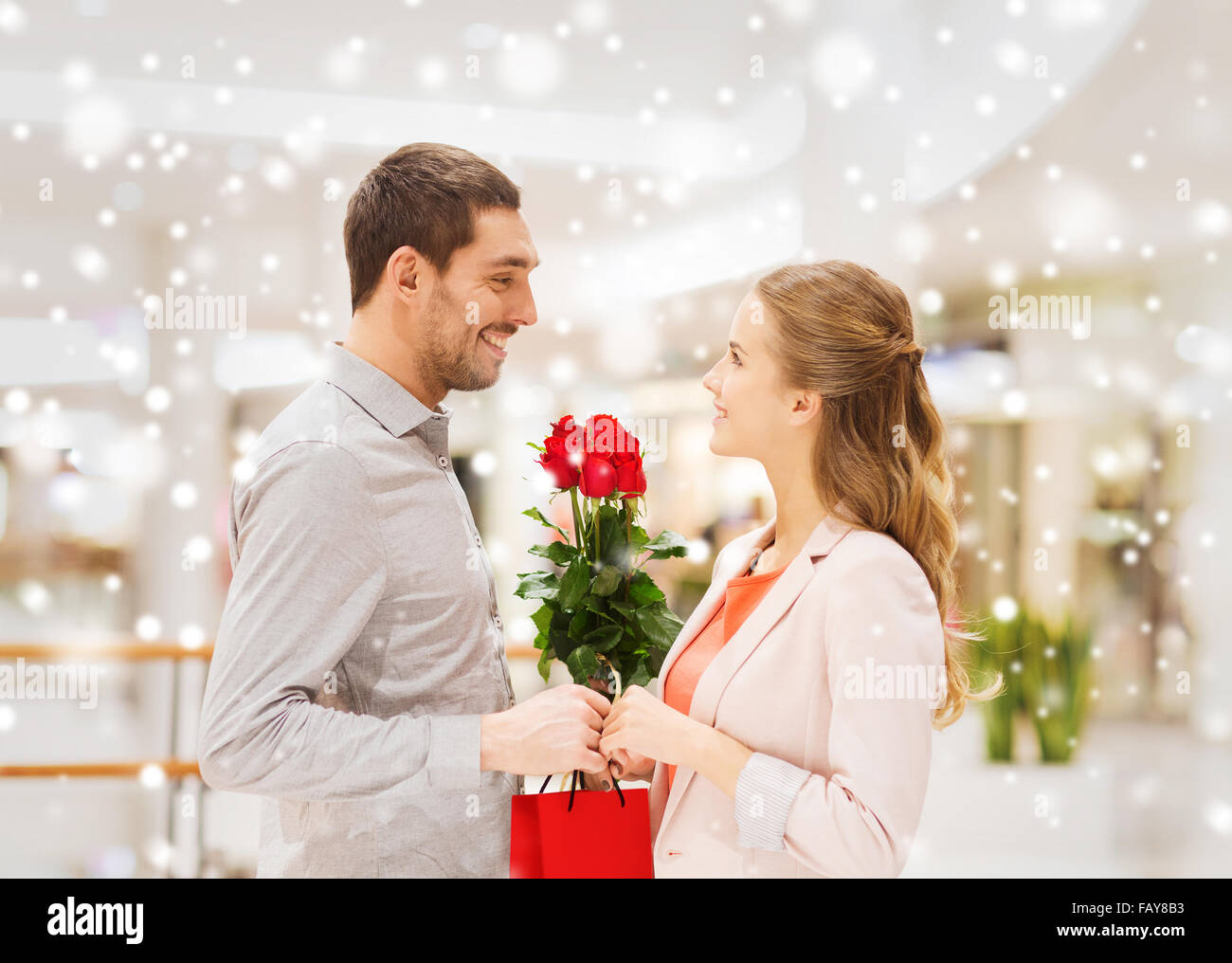 Had Giving Red Roses man giving woman red roses and present in mall Stock Photo - Alamy