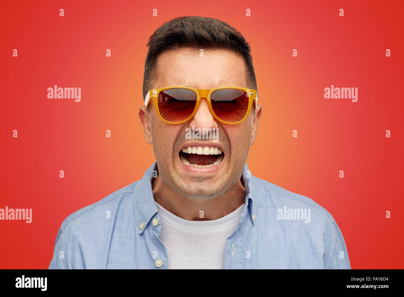 face of angry man in shirt and sunglasses over red Stock Photo