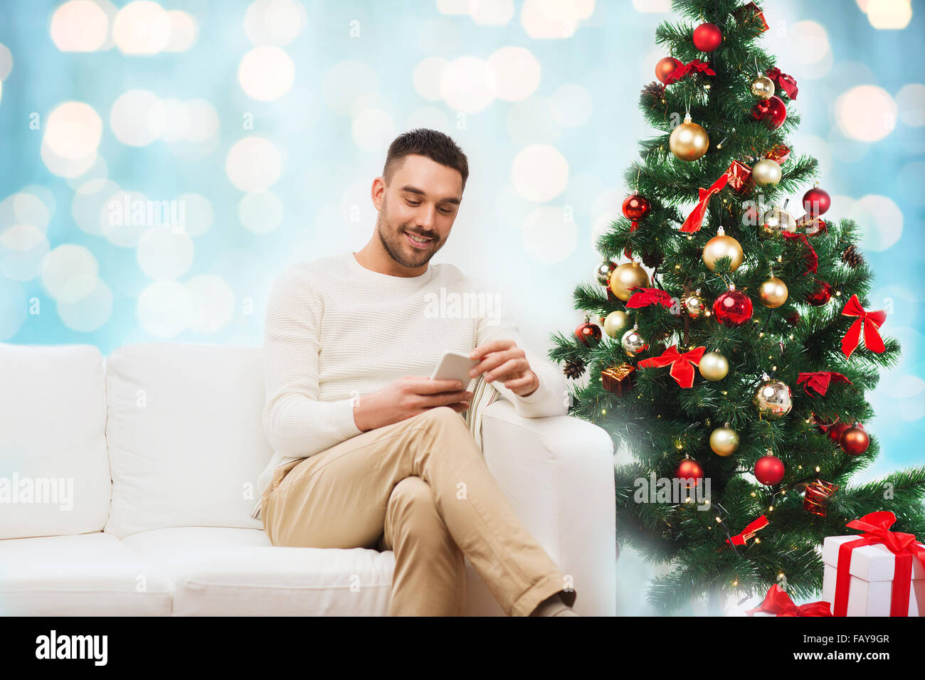 smiling man with smartphone over christmas lights Stock Photo