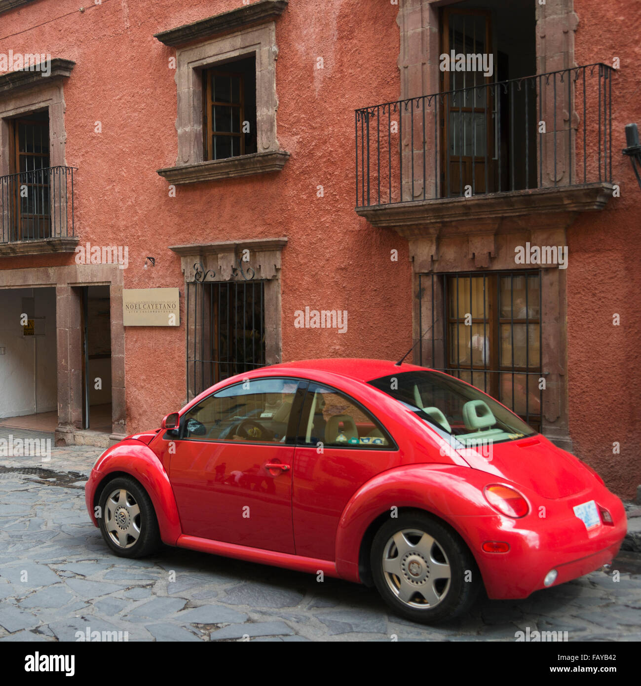 Red car parked outside a residential building; San Miguel de Allende, Guanajuato, Mexico Stock Photo