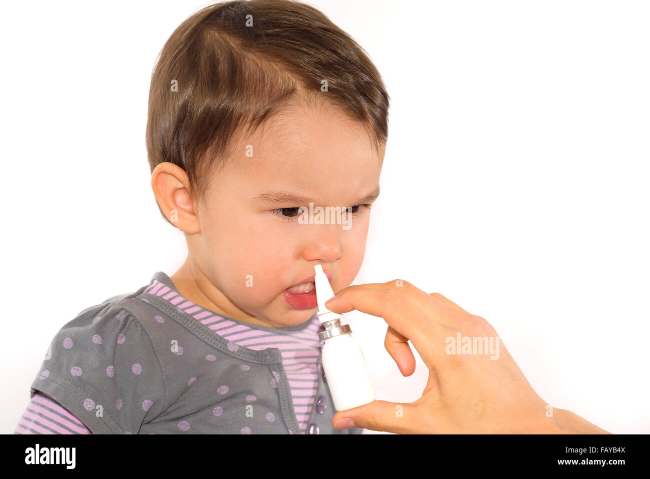 parent's hand of a girl applies a nasal spray Stock Photo