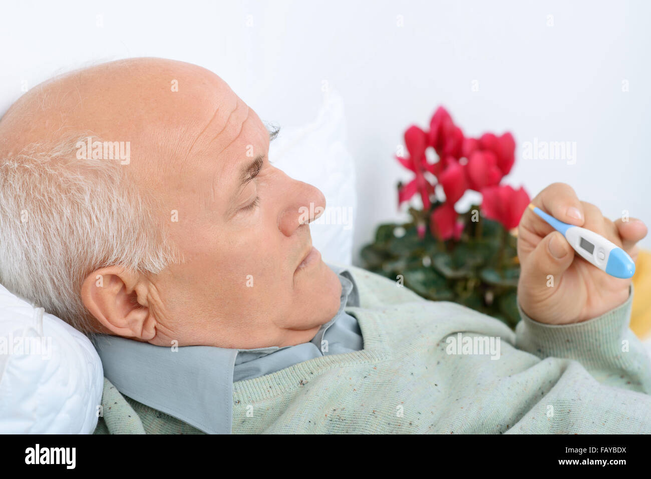 Senior gentelman checks the thermometer with a light scowl. Stock Photo