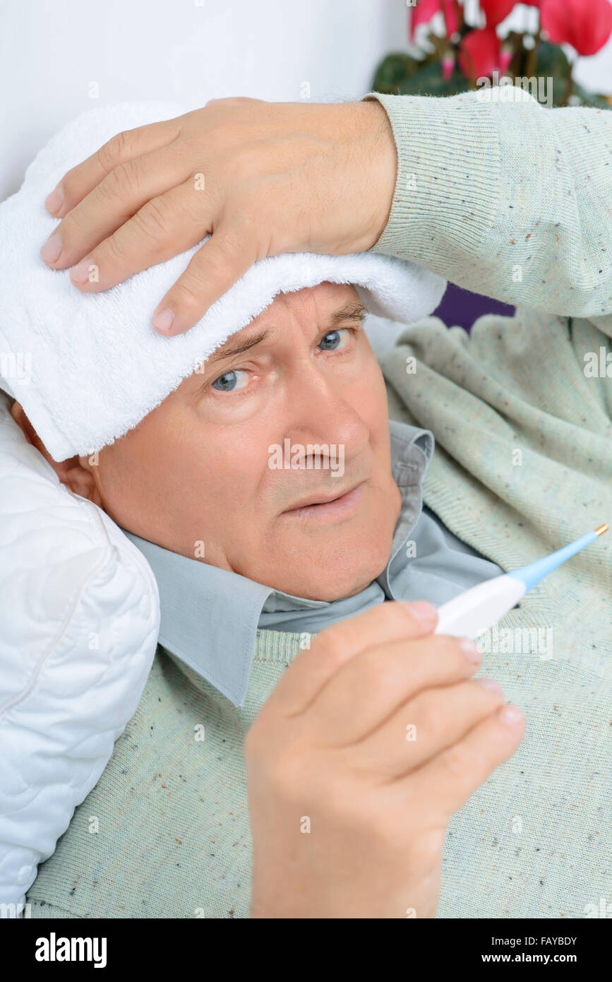 Gentleman uses wet towel while holding the thermometer. Stock Photo