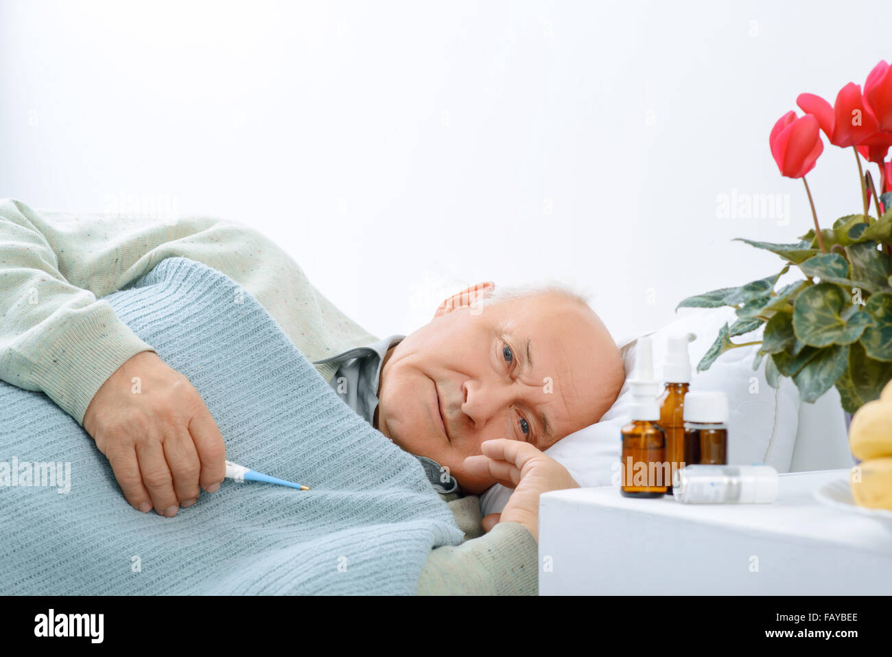 Senior aged man is resting while holding a thermometer. Stock Photo