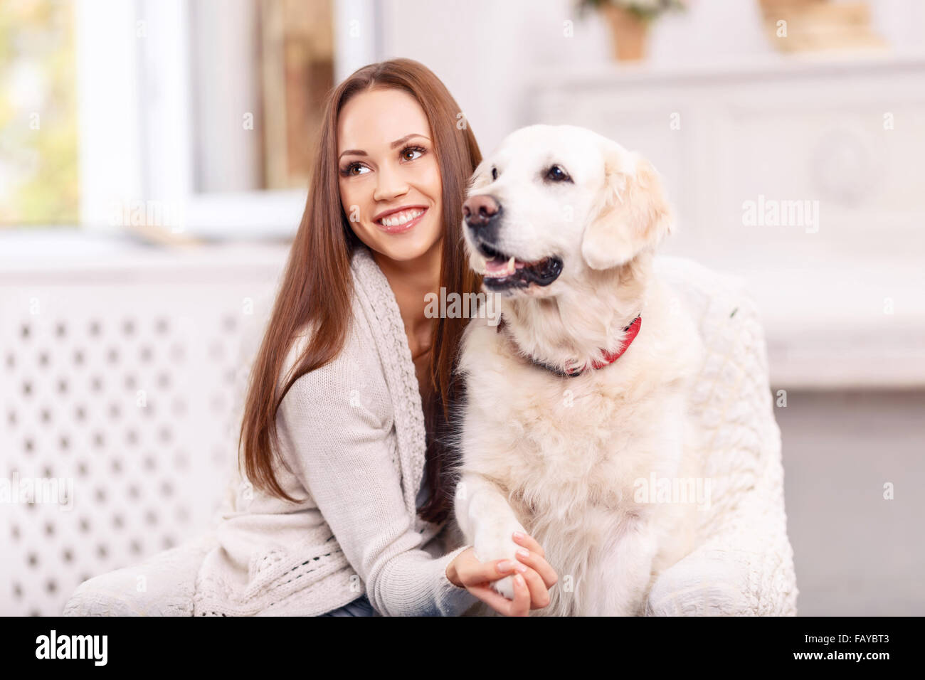 Lovely girl is smiling vividly while caressing a dog. Stock Photo