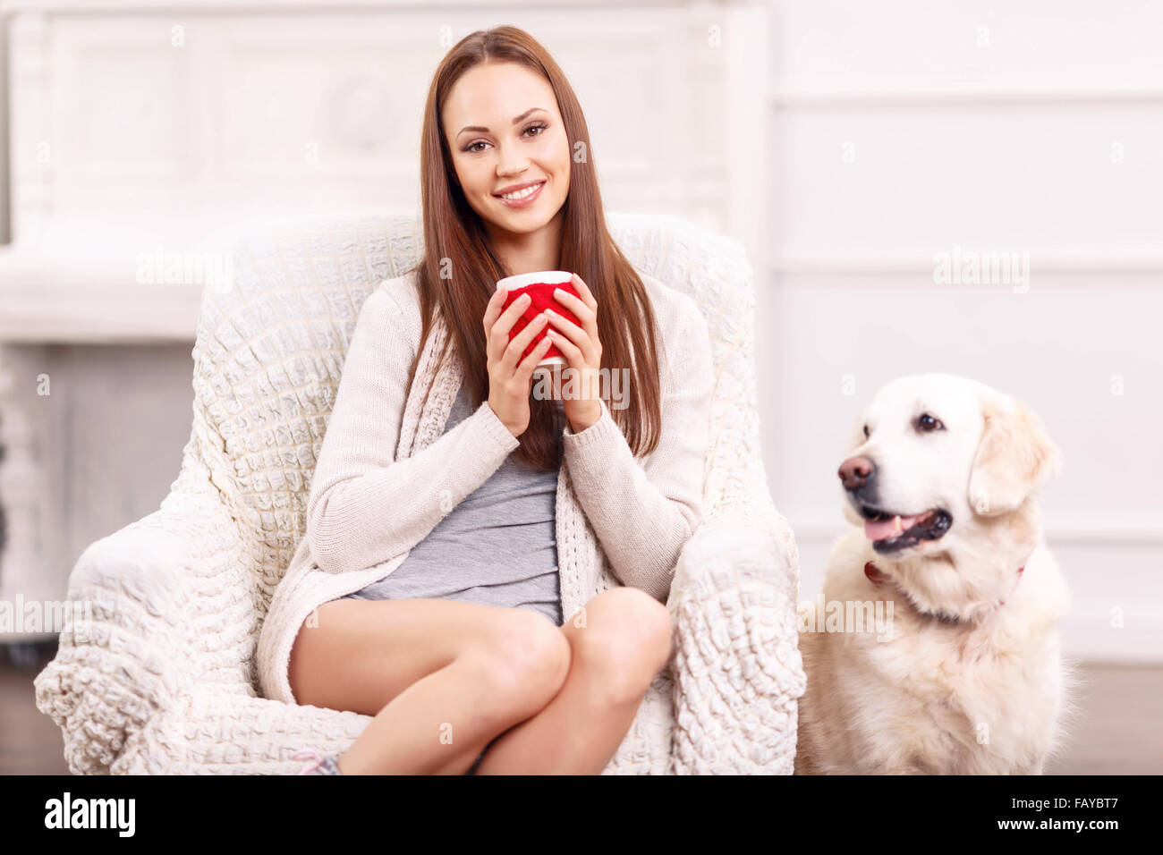 Pretty girl in the armchair with her pet around. Stock Photo