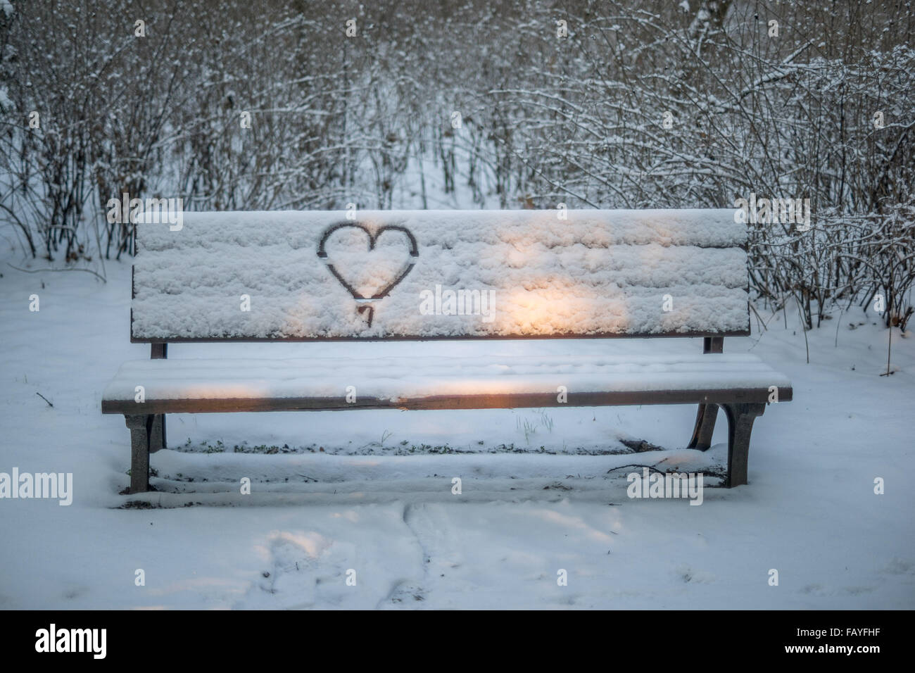 Snow-covered bench with a heart drawn on the back Stock Photo