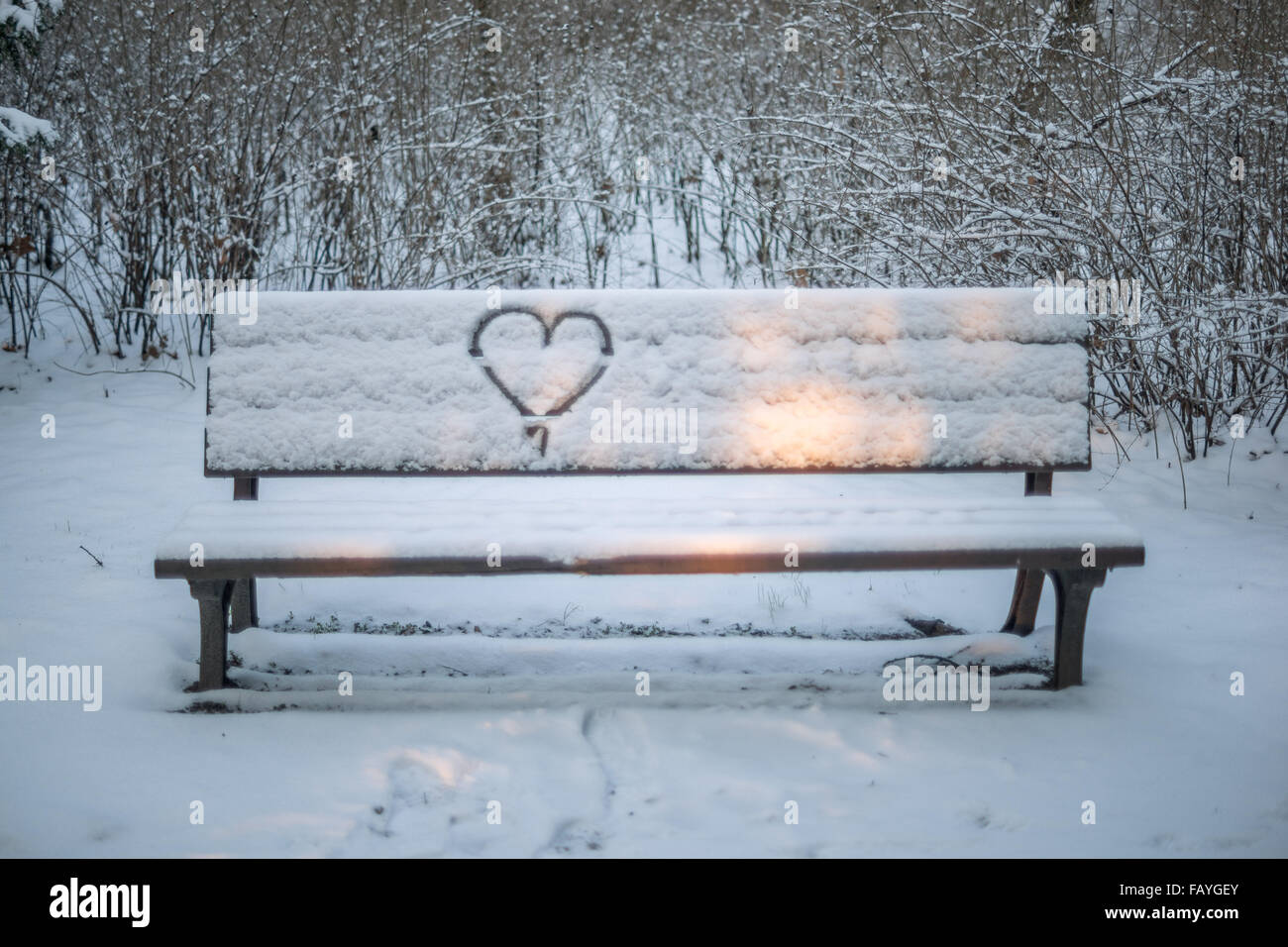 Snow-covered bench with a heart drawn on the back Stock Photo