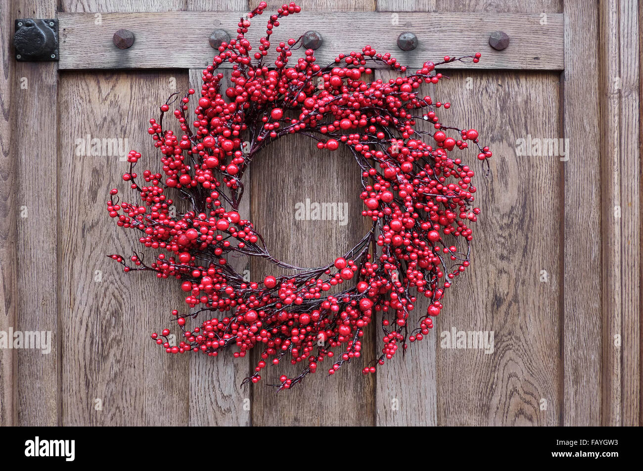 red berry style christmas wreath hanging on door Stock Photo