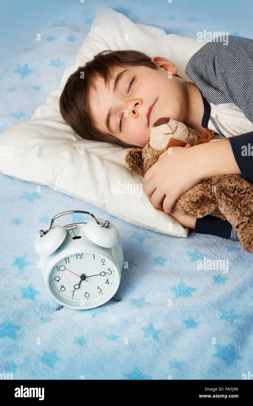 six years old child sleeping in bed with alarm clock Stock Photo Alamy