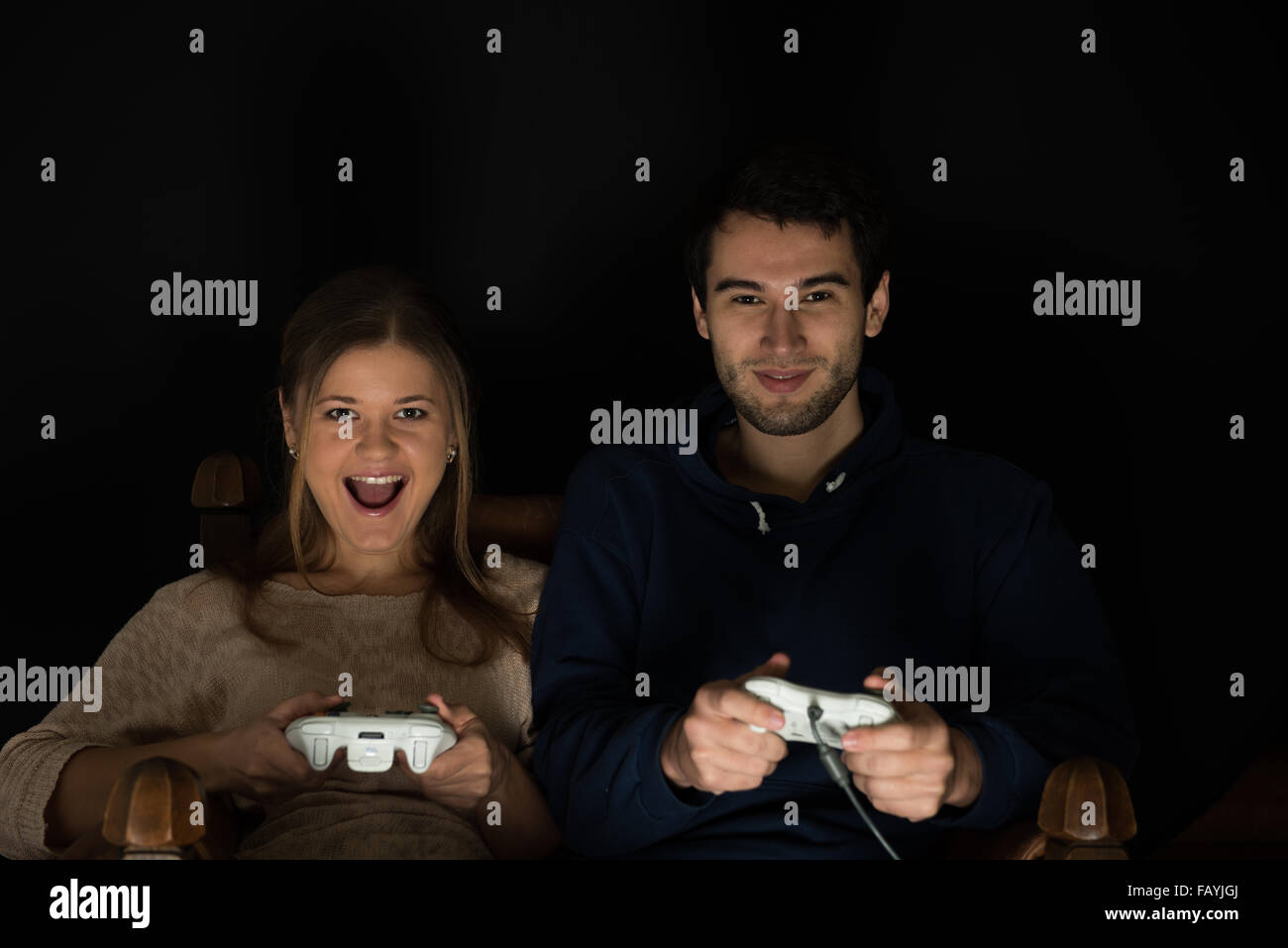 Young couple, man and woman play computer games sitting in dark room in ...